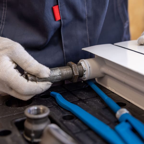 Gloved hands fitting a threaded pipe connection during an installation